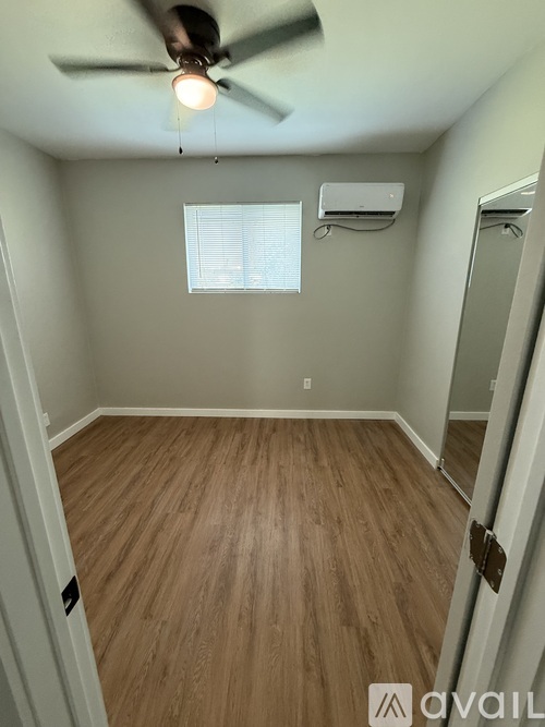 A room with a ceiling fan and wooden flooring.