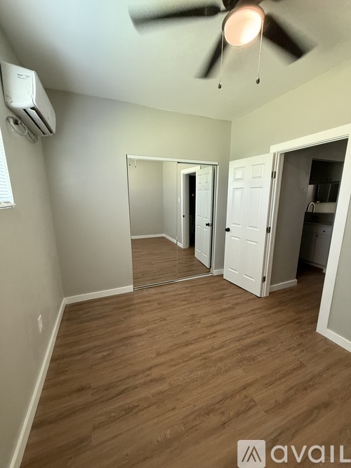 A room with a ceiling fan and wooden flooring.