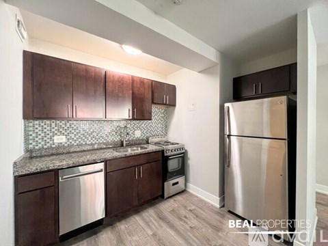 A kitchen with a refrigerator, sink, and cabinets.