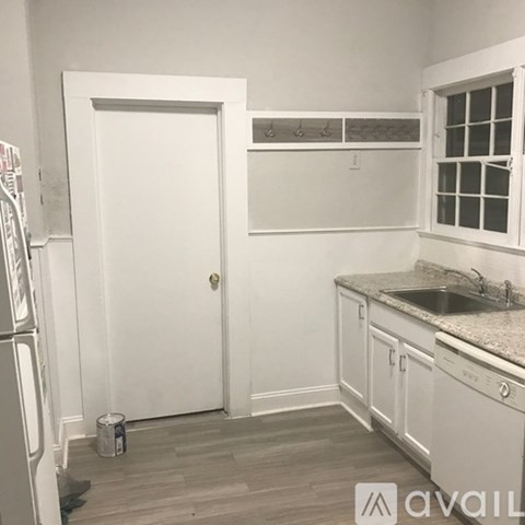 A kitchen with white cabinets and a white door.