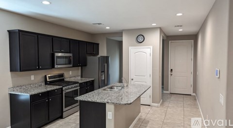 A kitchen with black cabinets and granite countertops.