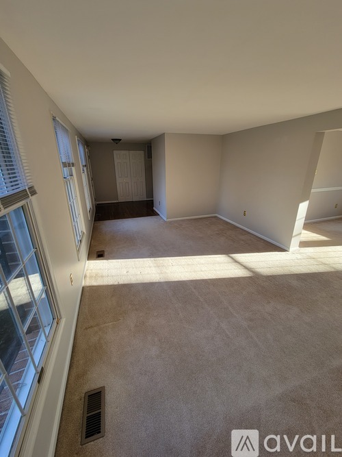 A room with a carpeted floor and a window on the left side.
