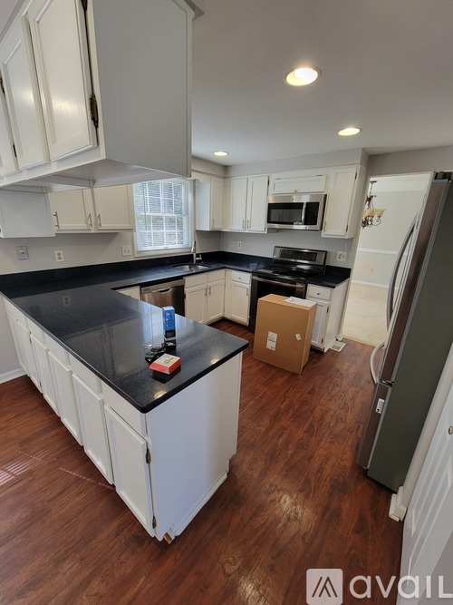 A kitchen with white cabinets and a black countertop.