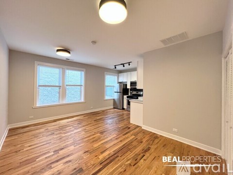 A spacious room with wooden flooring and a large window.