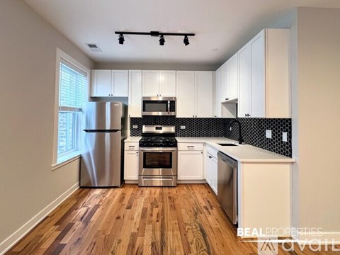 A kitchen with white cabinets and a black and white backsplash.