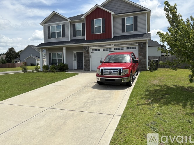 A red truck is parked in front of a two-story house.
