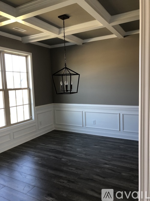 A room with a wooden floor and a hanging light fixture.