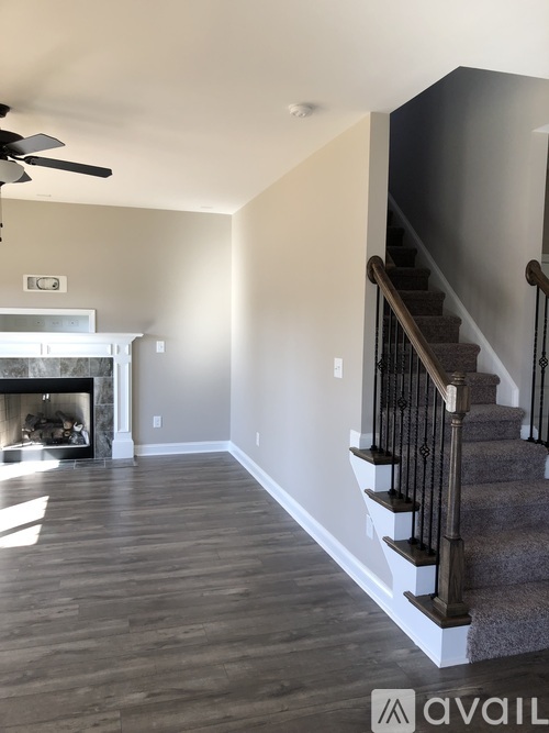 A living room with a fireplace and a staircase.
