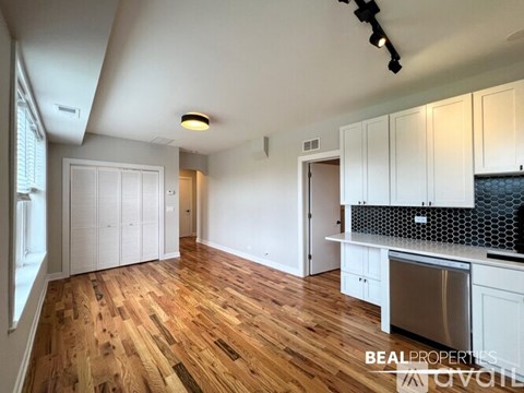 A kitchen with white cabinets and a wooden floor.