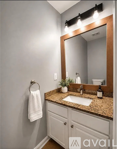 A bathroom with a sink, mirror, and a towel hanging on the wall.