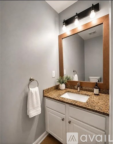 A bathroom with a sink, mirror, and a towel hanging on the wall.