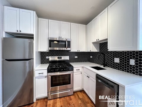 A kitchen with white cabinets and a black and white tiled backsplash.
