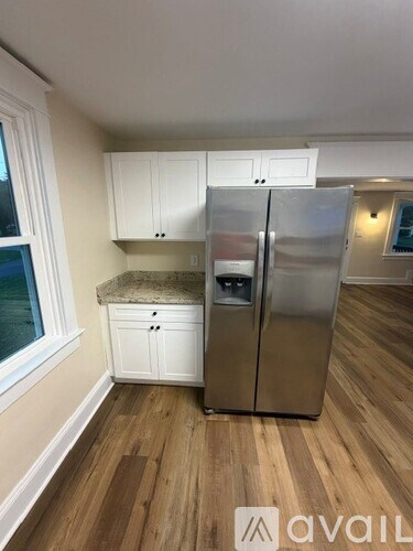 A kitchen with a refrigerator, cabinets, and a marble countertop.