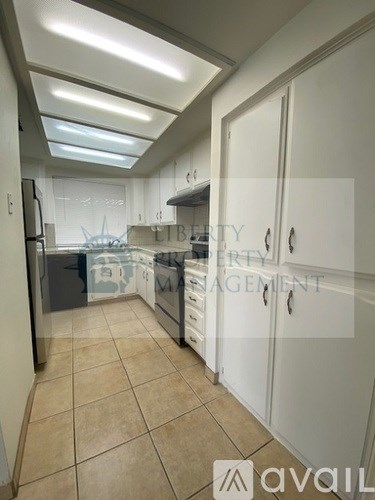 A kitchen with white cabinets and a tiled floor.
