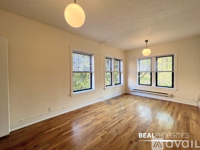 A room with wooden floors and three windows.