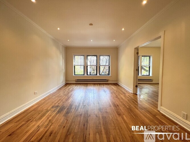 A spacious room with wooden floors and a large window.