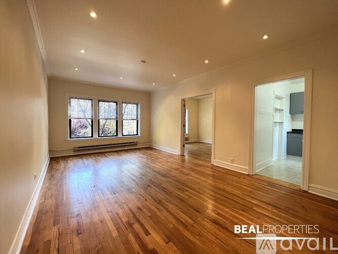 A spacious room with wooden flooring and a large window.