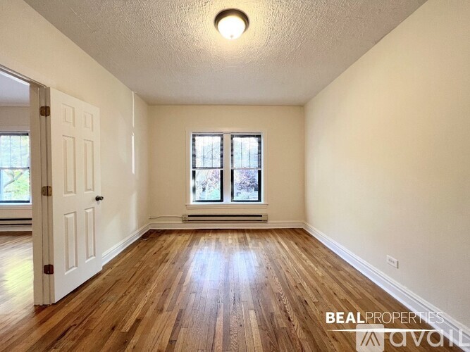 A room with wooden floors and a window with a view of trees.