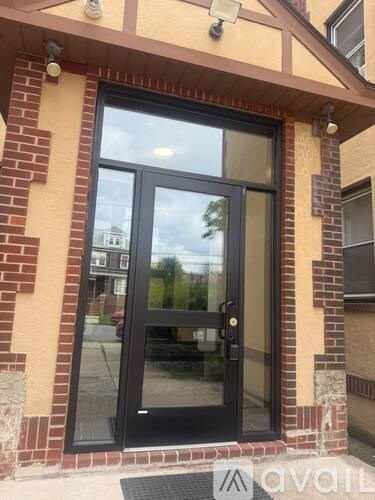 A black door with a glass window is set in a brick wall.