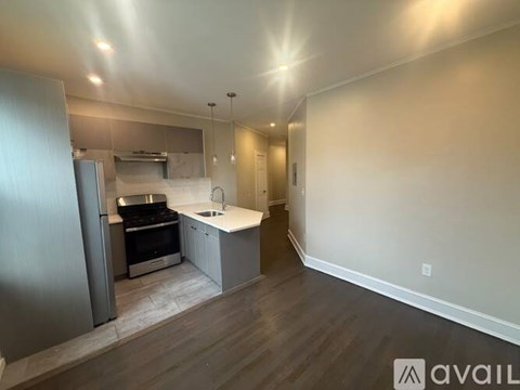 A modern kitchen with stainless steel appliances and a wooden floor.