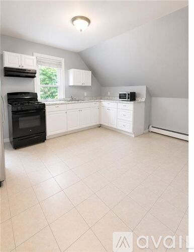 A kitchen with white cabinets and a black stove top oven.