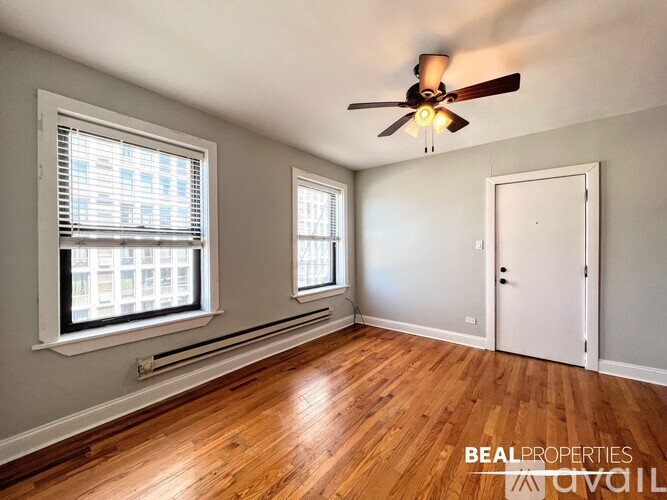 A room with a ceiling fan and two windows.