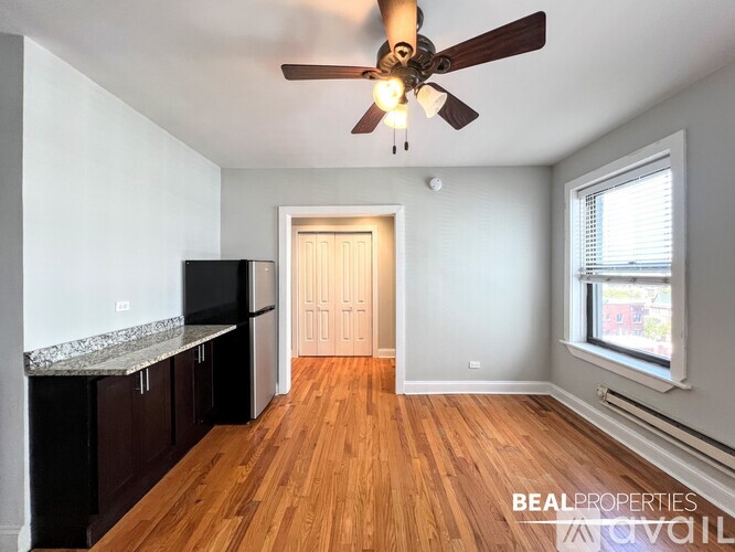 A BEALPROPERTIES photo of a room with wood floors and a ceiling fan.