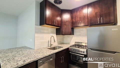 A kitchen with granite countertops and wooden cabinets is available for rent.