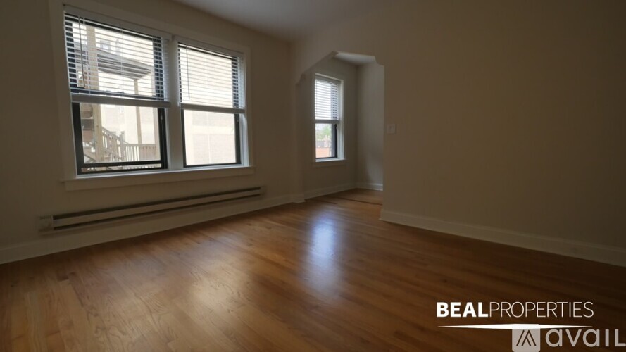 A room with wooden floors and two windows.