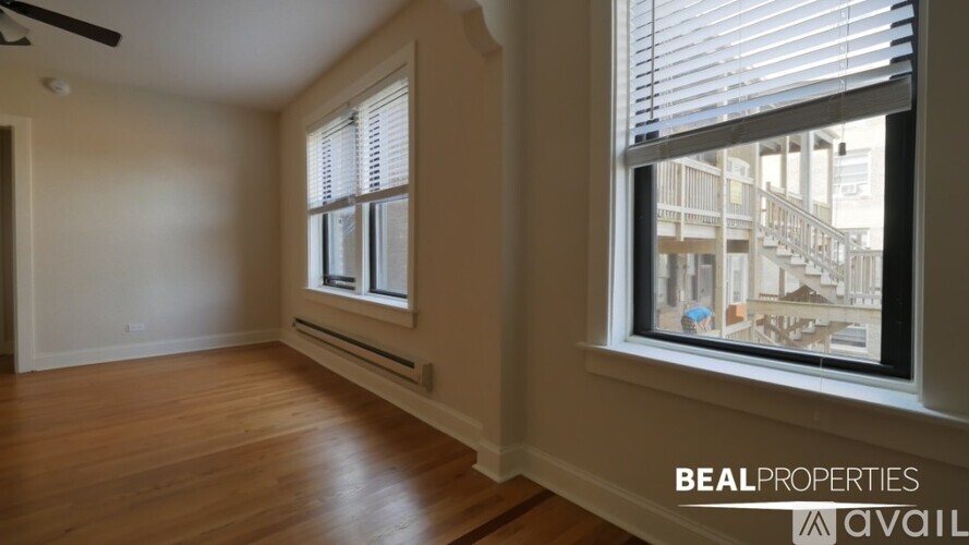 A room with wooden floors and a window showing a view of a building.