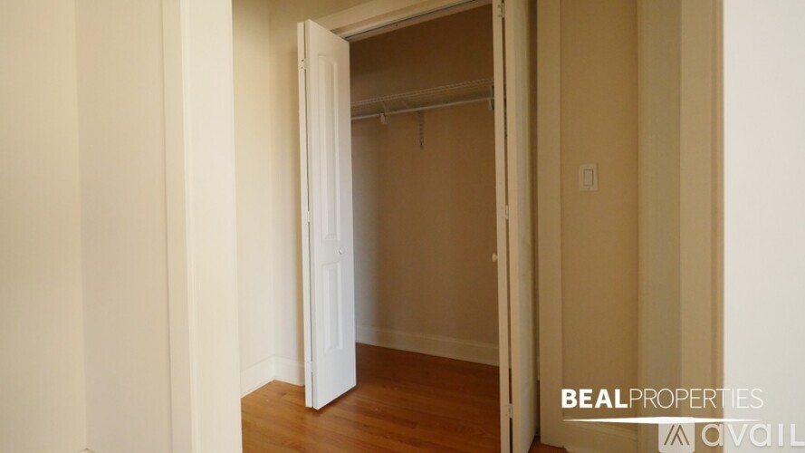 A white door is open to a room with a wooden floor.
