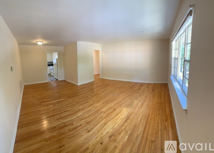 A spacious room with wooden flooring and a large window.