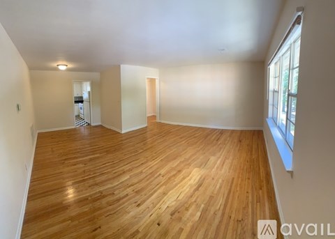 A spacious room with wooden flooring and a large window.