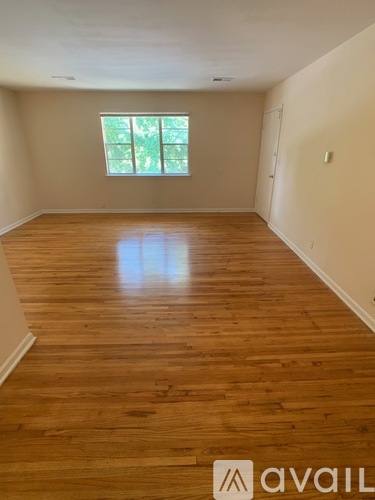 A room with wooden flooring and a window letting in natural light.