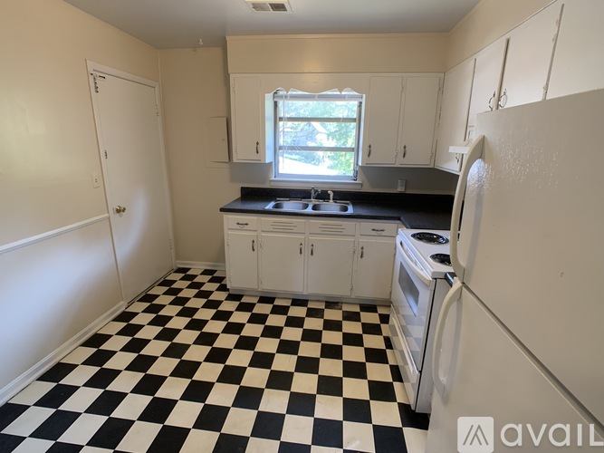 A black and white checkered floor in a kitchen with white cabinets and a window.