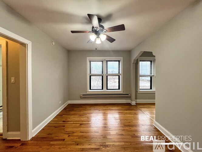 A room with a ceiling fan and two windows.