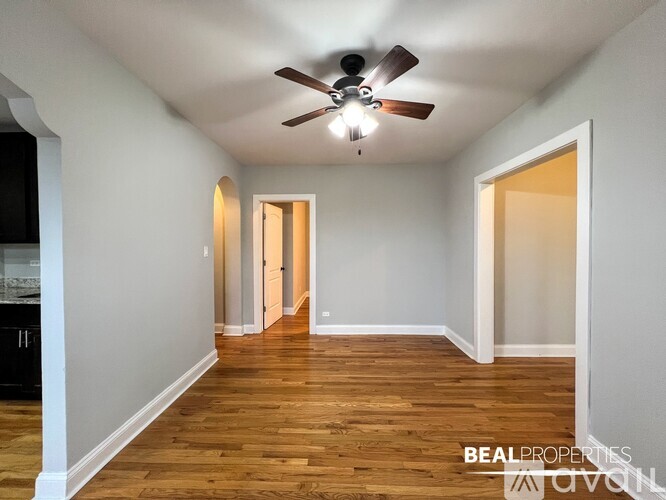 A spacious room with a ceiling fan and wooden flooring.