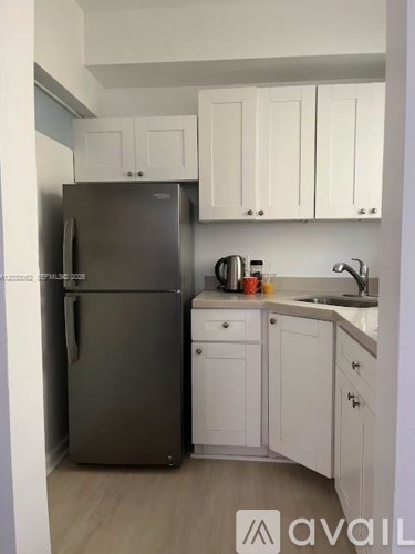 A kitchen with a fridge, cabinets and a counter.