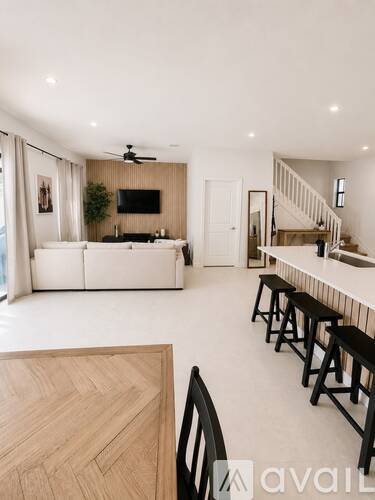 A modern living room with a white couch and a television on the wall.