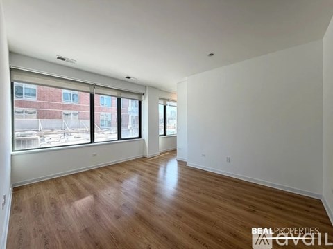 A spacious room with wooden flooring and large windows overlooking a marina.
