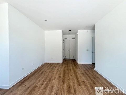 A room with wooden floors and white walls, with a door on the right side.