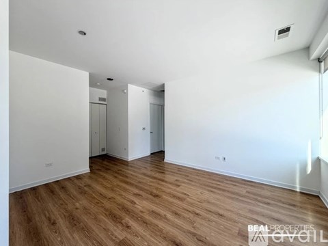 A spacious room with wooden flooring and white walls.