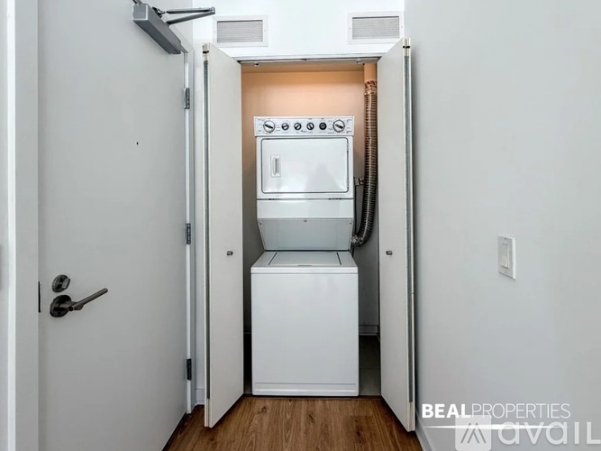 A white door is open to reveal a small kitchen with a dishwasher and oven.