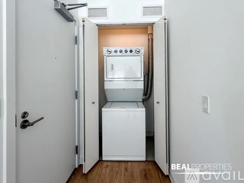 A white door is open to reveal a small kitchen with a dishwasher and oven.