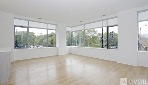 A spacious room with large windows and wooden flooring.