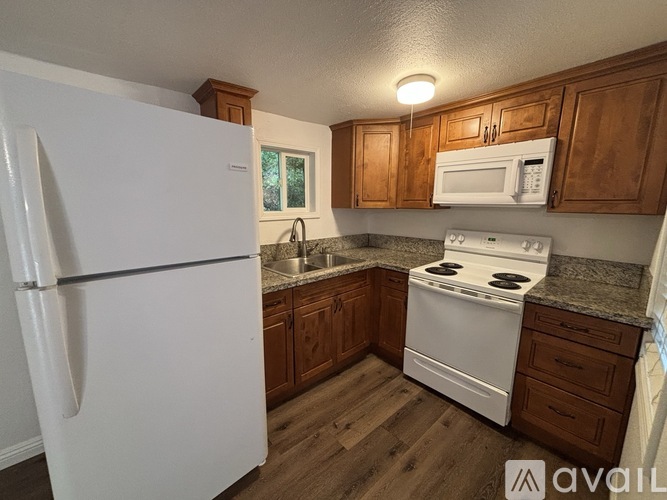 A kitchen with white appliances and wooden cabinets.