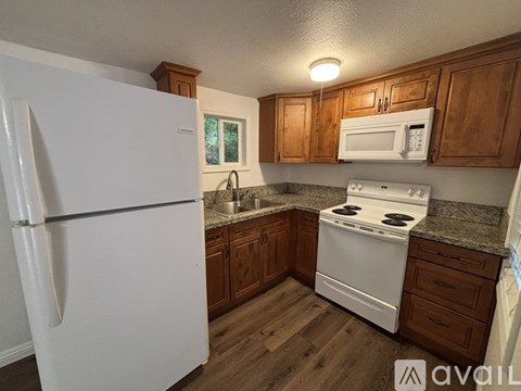 A kitchen with white appliances and wooden cabinets.