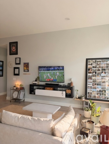 A living room with a white couch and a television on a stand.