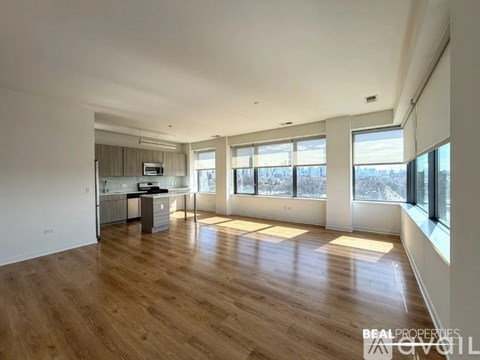 A spacious living room with wooden floors and large windows.