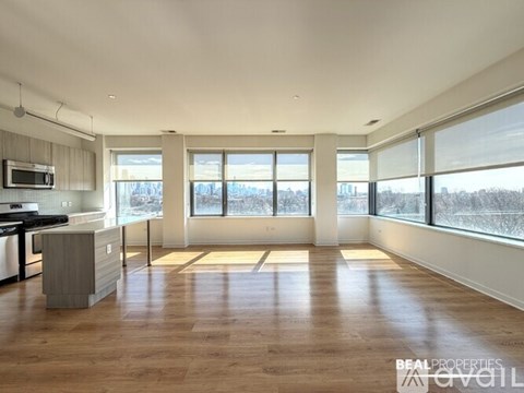 A spacious, empty living room with hardwood floors and large windows.